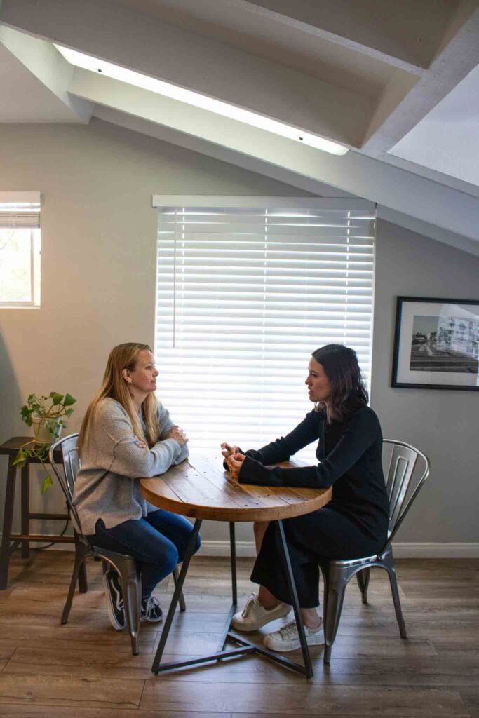 Photo of two young women talking at a table while at a teen mental health php in Los Angeles